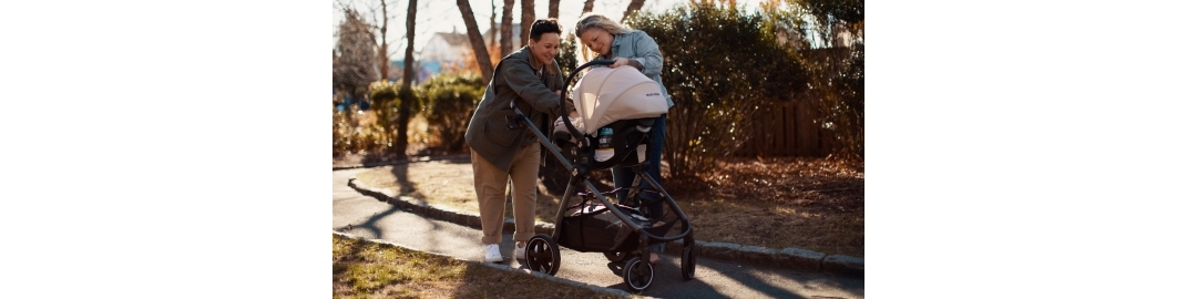 Two women pushing stroller smiling at baby